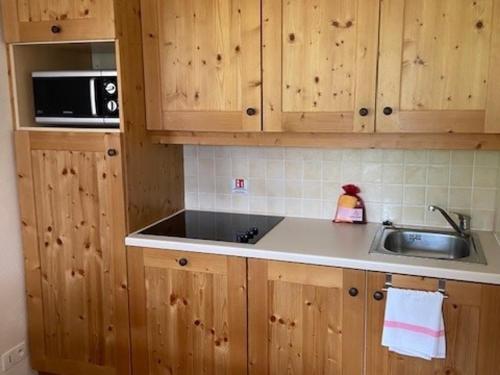 La cuisine est équipée de placards en bois, d'un évier et d'un four micro-ondes. dans l'établissement Appartement 6 personnes au pied des pistes avec piscine à Val Cenis - FR-1-508-256, à Lanslebourg-Mont-Cenis