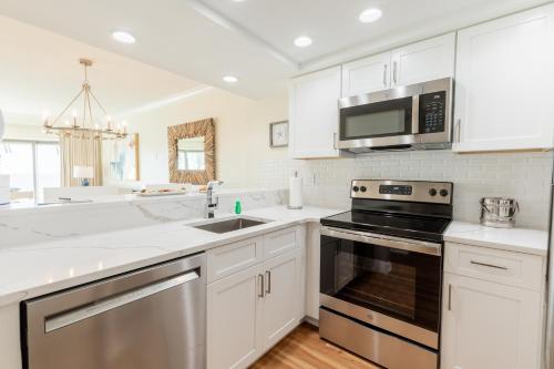 a kitchen with white cabinets and stainless steel appliances at La Mer Beachfront Resort in Cape May