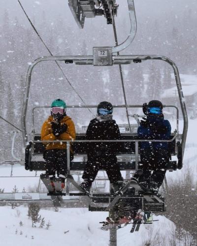 three people on a ski lift in the snow at Elite Hotel -Downtown Center- "Ski & Northern light Tour" "Hot Spring Tour "Long-term stay" in Whitehorse