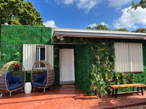 a building covered in green ivy with two chairs and a bench at Art Gardens AIRPORT 4 MI FROM THE MIA in Miami