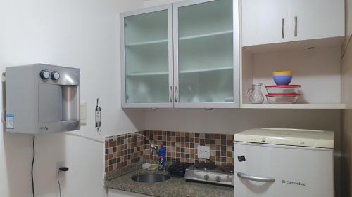 una cocina con armarios blancos y fregadero en Ed. Boulevar Antares II, en Brasilia