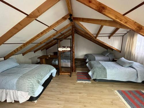 2 łóżka w pokoju na poddaszu z drewnianymi belkami stropowymi w obiekcie Cabañas "El Cazador" w mieście Futaleufú