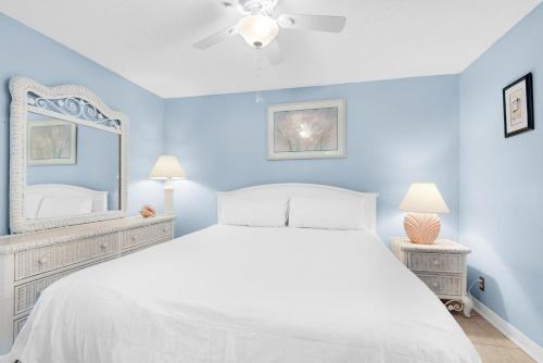 1 dormitorio con cama blanca y espejo en Sunbird 1106W en Panama City Beach