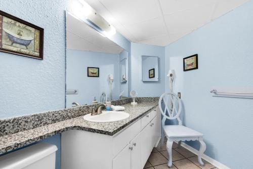 a bathroom with a sink and a mirror and a chair at Sunbird 1106W in Panama City Beach