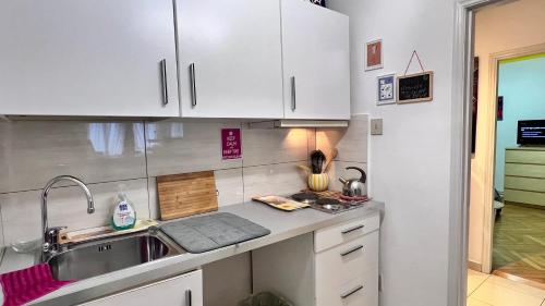 a kitchen with white cabinets and a sink at Behind On The Canalside Venice in Venice