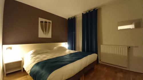 a bedroom with a large bed with blue curtains at Etesia in Feurs