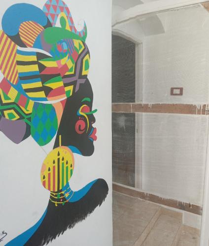 Golden nubian guesthouse في أسوان: غرفة بها لوحة على الحائط