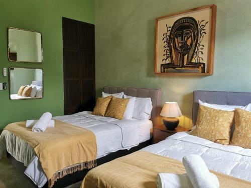 two beds in a room with green walls at Casa Mara 53 Luxury House in downtown Mérida in Mérida