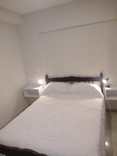 1 dormitorio con 1 cama blanca y 2 mesitas de noche en Departamento 2 ambientes céntrico en Tucumán en San Miguel de Tucumán