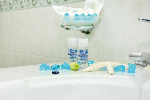 a bathroom sink with a pile of toiletries on it at Hotel Capizzo in Ischia