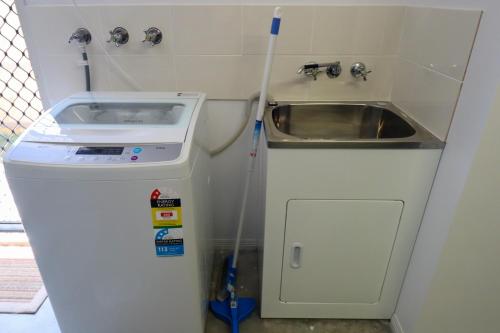 eine kleine Küche mit einem Waschbecken und einem Waschbecken in der Unterkunft BLK Stays Guest House Deluxe Units Morayfield in Morayfield