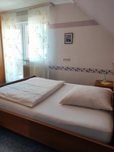 a bedroom with a large white bed with a window at Gasthaus "Zur frischen Quelle" in Laubach