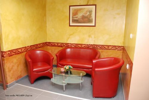 a waiting room with two red chairs and a table at B&B Vila Tamaris in Zaječar