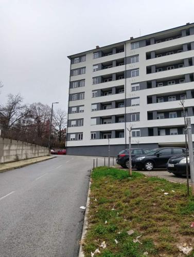 a large white building with cars parked in a parking lot at Welcome Apartments in Niš
