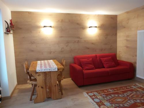 sala de estar con sofá rojo y mesa en La petite maison, en La Thuile