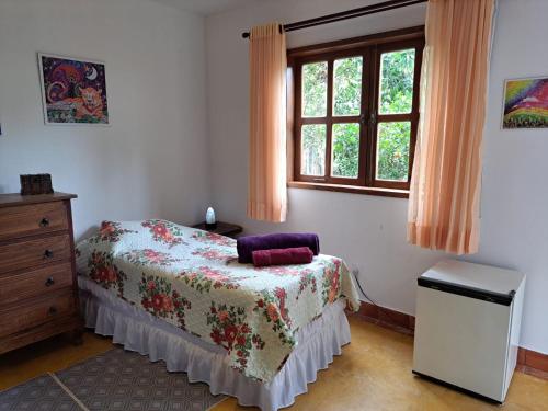 a bedroom with a bed and a window at Suite Solteiro Cristal Rosa, Suites Ananda in Alto Paraíso de Goiás