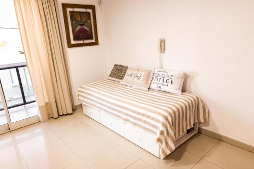 Bett mit gestreifter Decke in einem Zimmer mit Fenster in der Unterkunft COSTANERA APART in Villa María