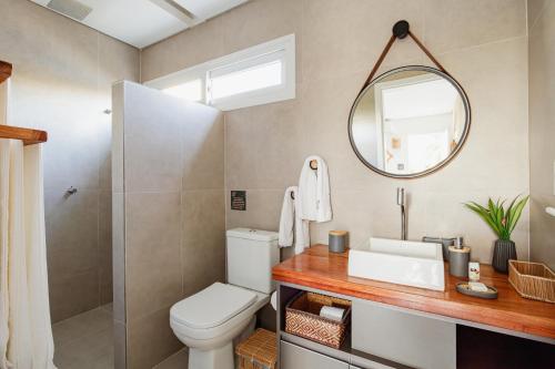 a bathroom with a toilet and a sink and a mirror at VILA PITHAYA - Casa Jambo Rosa in Japaratinga