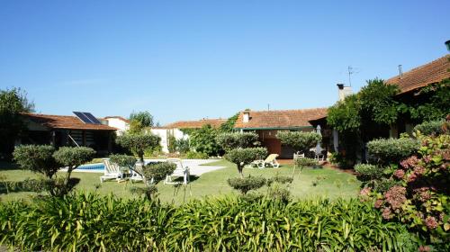 a house with a yard with chairs and trees at Casa Rural Oliveira do Bairro in Oliveira do Bairro