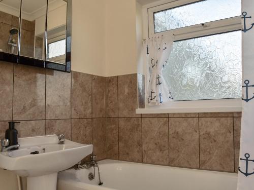 a bathroom with a sink and a tub and a window at Beach Walk in Kessingland