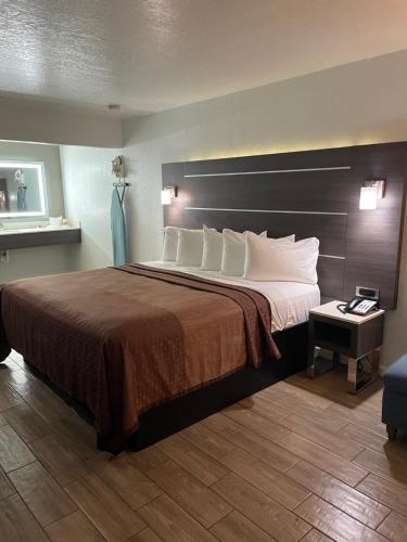 um quarto de hotel com uma cama grande e uma cabeceira castanha em Econo Lodge Inn & Suites Near Lackland AFB em San Antonio