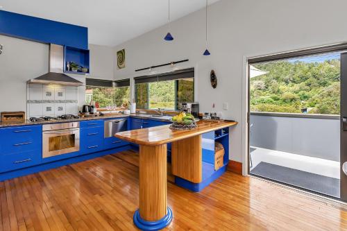 ファンガレイにあるMi Castillo on Hatea Driveのキッチン(青いキャビネット、木製テーブル付)