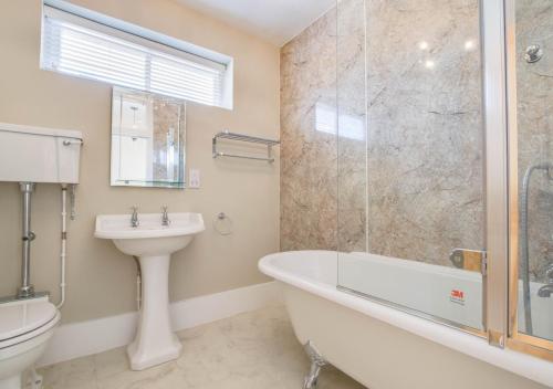 a bathroom with a tub and a sink and a toilet at 4 Lambseth Street in Eye