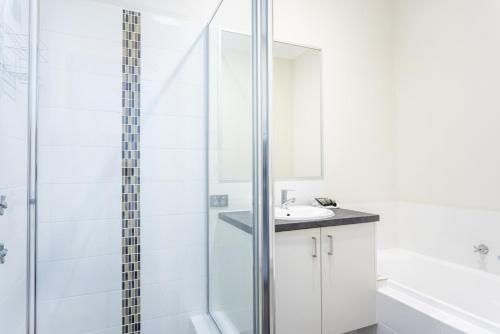 een witte badkamer met een douche en een wastafel bij Bambili Place - EXECUTIVE ESCAPES in Perth