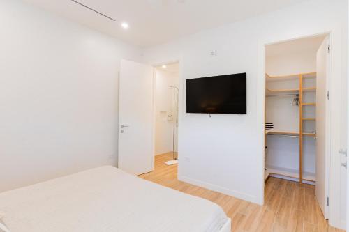a white bedroom with a bed and a flat screen tv at ONE Canal Point in Upper Land