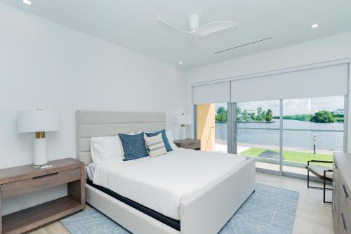 a white bedroom with a bed and a large window at ONE Canal Point in Upper Land
