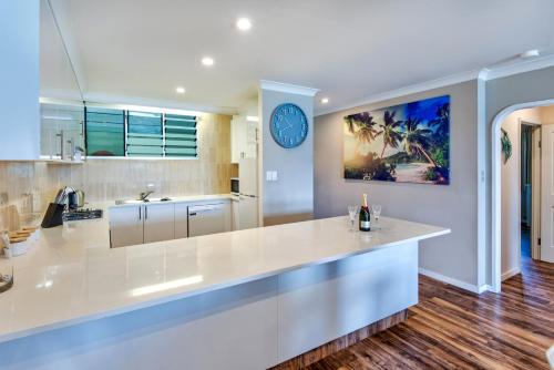 uma cozinha com um grande balcão branco e um relógio na parede em Beach Lodges em Hamilton Island