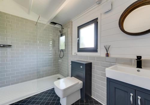 a bathroom with a sink and a toilet and a tub at Woodpecker Lodge in Stradbroke