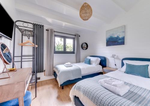 a bedroom with two beds and a desk and a tv at Woodpecker Lodge in Stradbroke