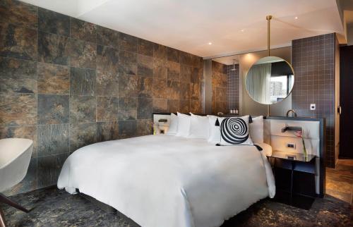 a bedroom with a large white bed and a mirror at SO/ Auckland in Auckland
