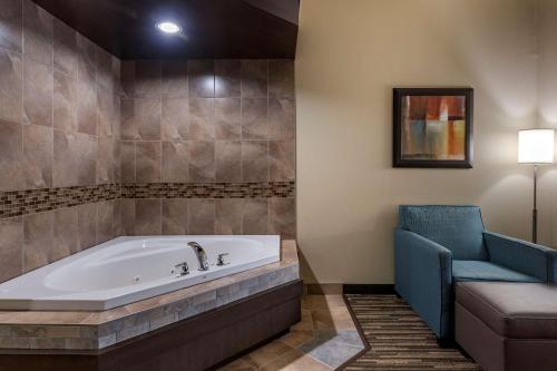 Best Western Dartmouth Hotel & Suites في هاليفاكس: حمام مع حوض استحمام وكرسي أزرق
