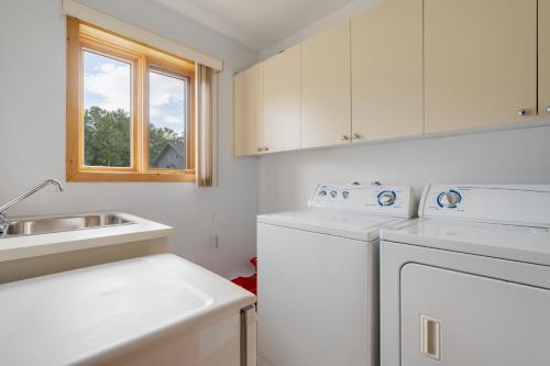 a white kitchen with a dishwasher and a sink at MontFJORD - Chalets, vue spectaculaire et SPA. ChantaFJORD #4 in Sacré-Coeur-Saguenay