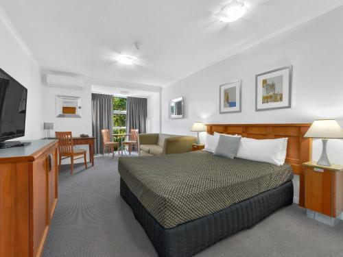 1 dormitorio con 1 cama y sala de estar en Airport Heritage Motel, en Brisbane