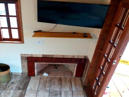 a living room with a fireplace with a flat screen tv at Chalé Som do Riacho com Hidromassagem e Lareira á 20 minutos de Gonçalves mg in Gonçalves
