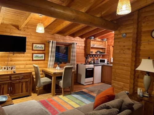 a living room with a table and a kitchen at Riverside Lodge in Killiecrankie in Bridge of Tilt