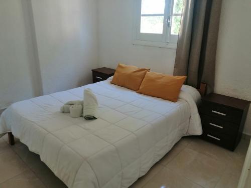 a bedroom with a large white bed with two pillows at Gran Colonial Riviera in Piriápolis