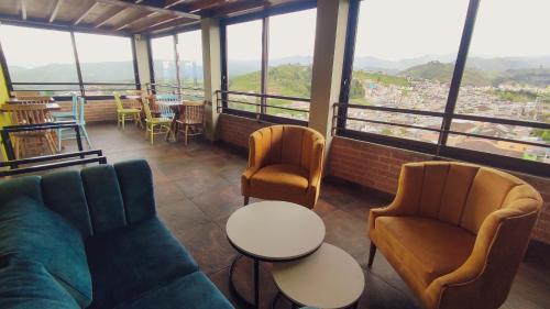 Hotel Entre Brumas في Aguadas: غرفة بها كنب وكراسي وطاولات ونوافذ