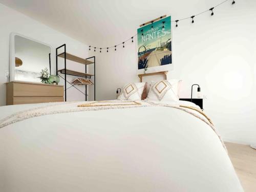 une chambre blanche avec un lit et une affiche sur le mur dans l'établissement L'Imperti'Nantes, à Nantes