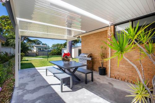 a patio with a table and benches and a brick wall at Sea and Sun Pet Friendly 4 Mins to Beach in Callala Beach