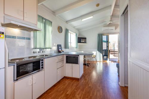 a kitchen with white cabinets and a wooden floor at BIG4 Breeze Holiday Parks - Port Hughes in Port Hughes