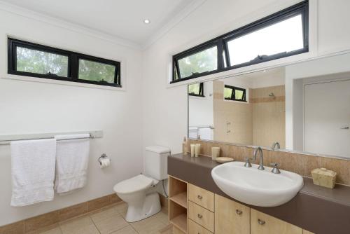 a bathroom with a sink and a toilet and a mirror at Naiad 12 in Rainbow Beach