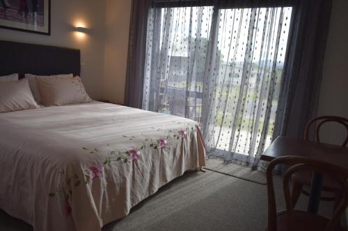 a bedroom with a bed and a large window at Paradise In Whitianga B & B in Whitianga