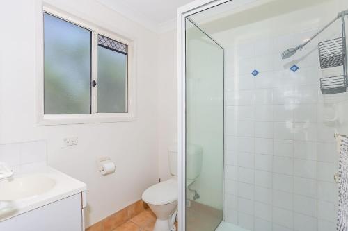 a white bathroom with a toilet and a shower at Rainbow Tides in Rainbow Beach