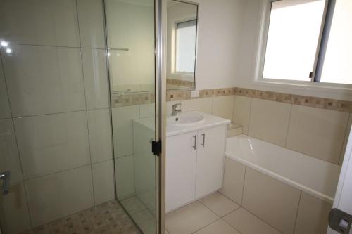 a bathroom with a shower and a sink and a tub at 62 Tingira Close - Modern lowset home with swimming pool, outdoor area, ample parking. Pet friendly in Rainbow Beach