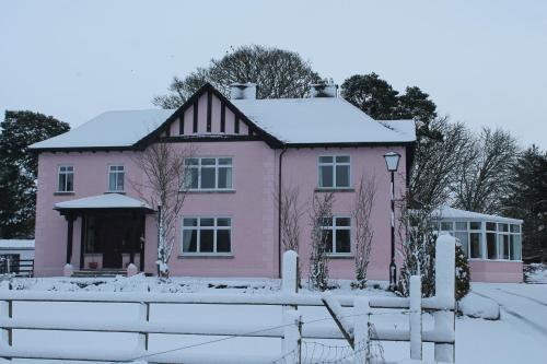 a pink house in the snow with a fence at Riversdale Farm B&B in Ballinamore