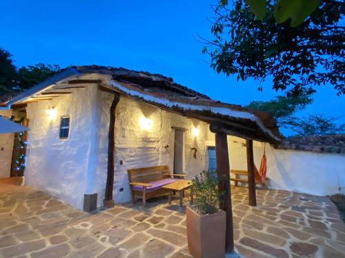 a small white building with a table and a bench at El Principito Hospedaje in Barichara